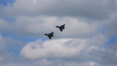 two eurofighters fly one behind the other in slow motion through the cloud-covered sky. taken at the air show called airpower 2024