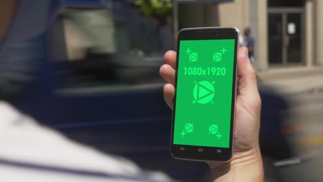 vista diurna de un hombre usando un teléfono inteligente de pantalla verde