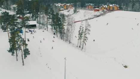 people in multicolored ski suits move down big snowy slope