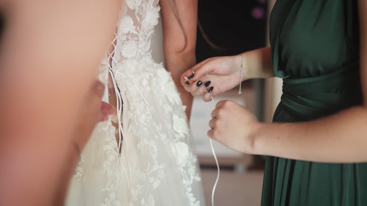 Bride prepares in lace dress surrounded by bridesmaids, joyful occasion