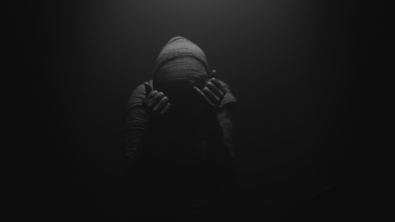 A mummy of a woman on a dark backdrop turns her head