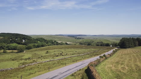 aerial high to low, view of an asphalt road through the rural countryside of dartmoor, uk