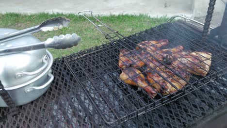 marinated chicken being barbecued on open fire with a grid