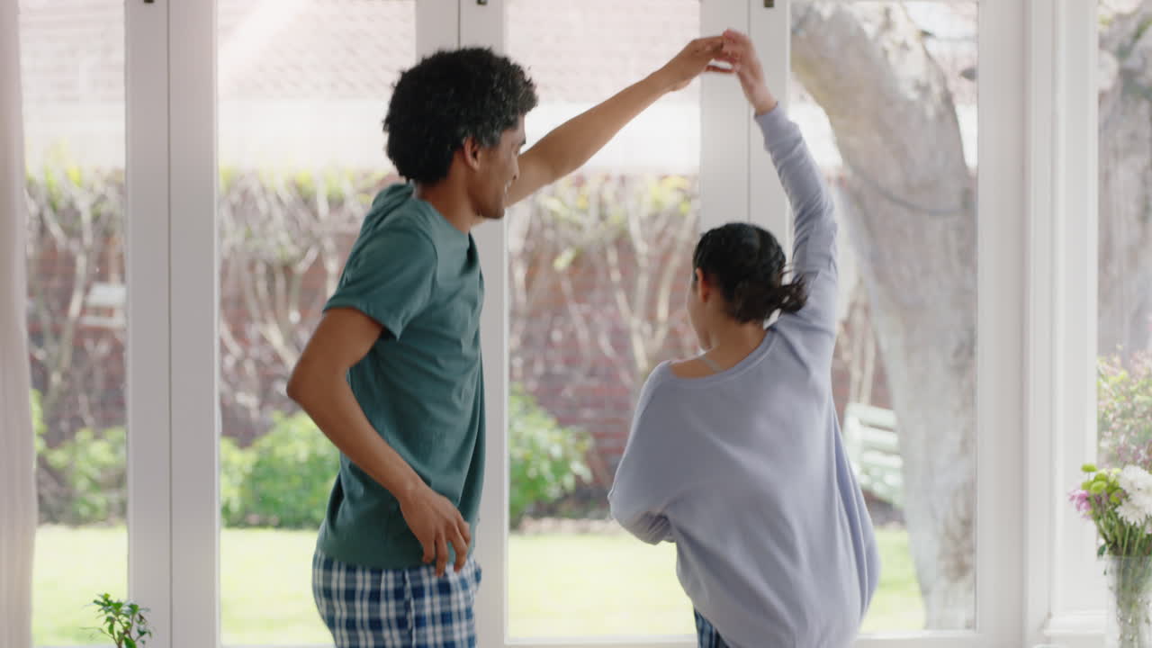 happy father dancing with teenage daughter having fun enjoying playful dance enjoying weekend celebration at home wearing pajamas