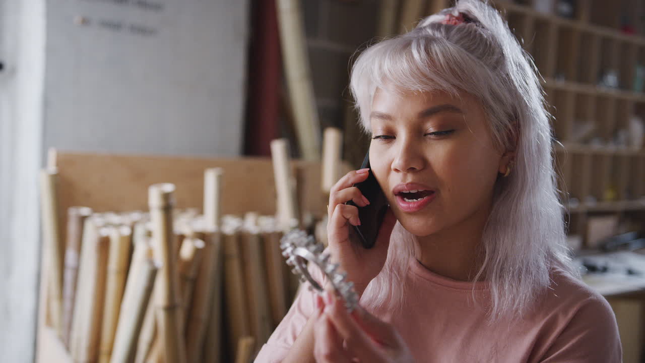 propietaria de un negocio en un taller haciendo una llamada por teléfono móvil para discutir el componente