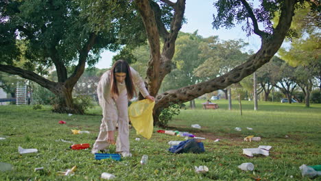 girl participate park cleanup holding yellow bag. woman collecting trash nature