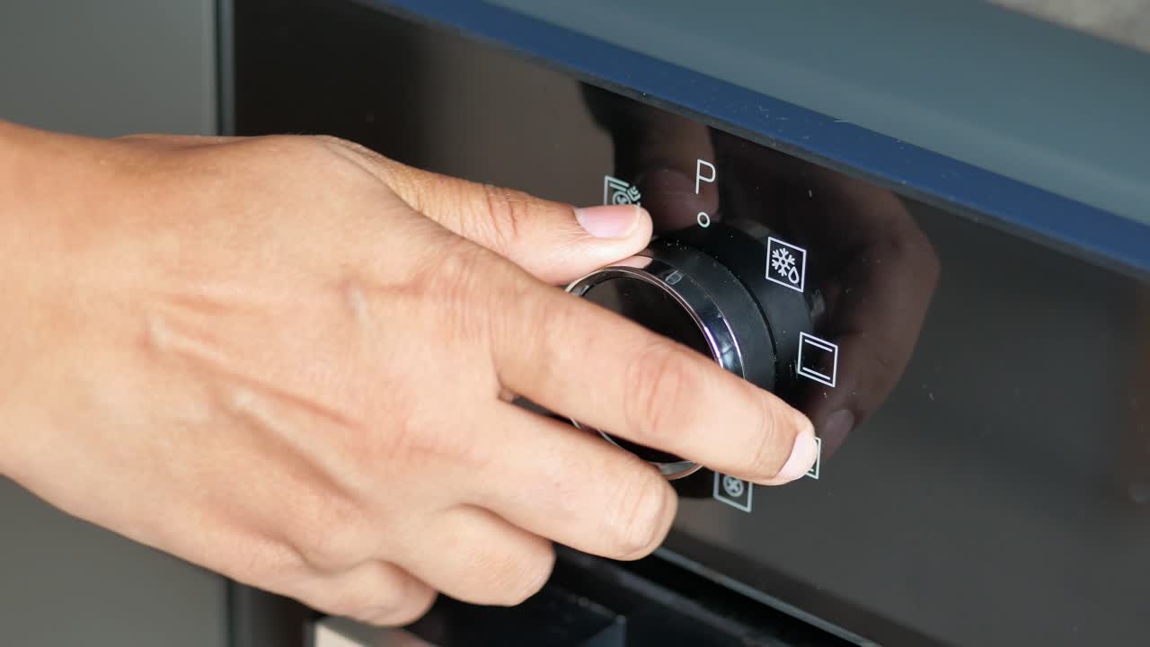 오븐에 온도 조절을 설정하는 여성의 손