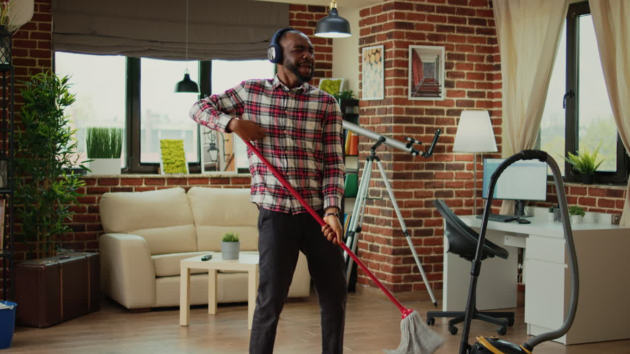 African american person using mop to wash wooden floors
