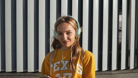 retrato de una joven linda y atractiva en el fondo urbano escuchando música con auriculares. mujer con blusa amarilla y falda plateada