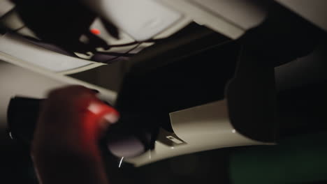 vista de una mujer abriendo una caja del techo del coche y recuperando gafas por la noche. la escena captura el momento en que su mano con uñas pintadas de negro interactúa con la caja del tejado del coche