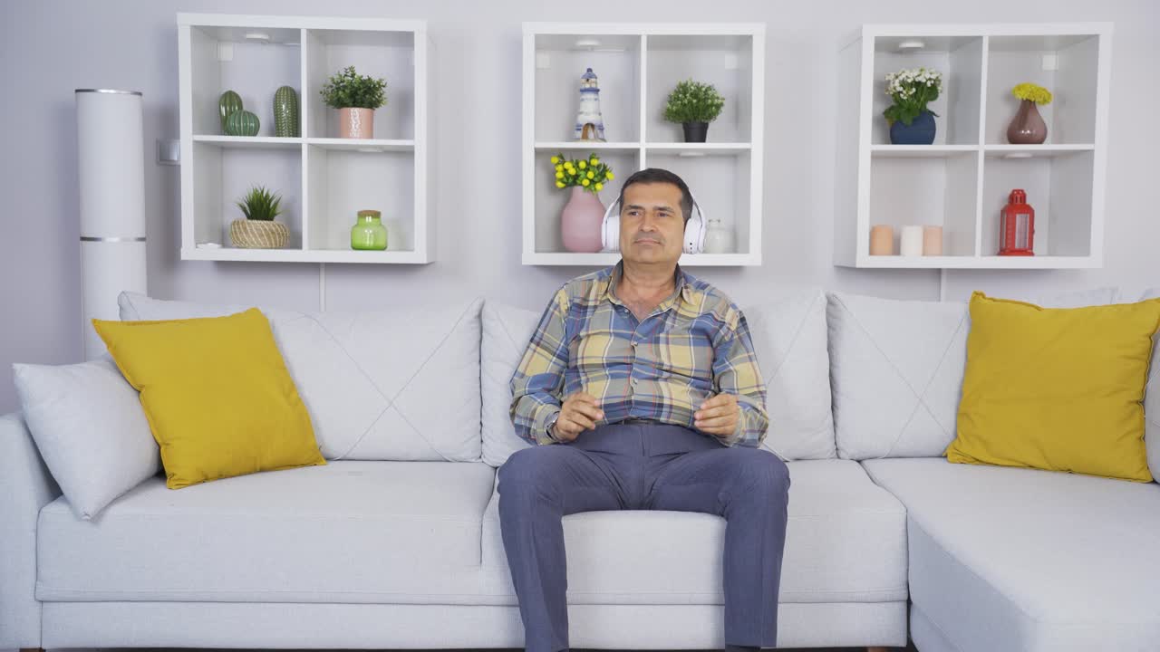 un anciano feliz en casa escuchando música tranquilamente con los auriculares.