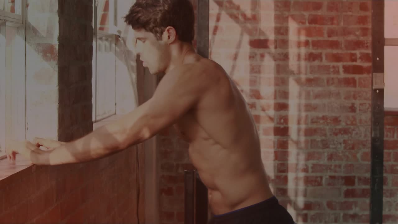 Shirtless fitness man reacting to camera pan, rising, turning, celebrating workout, sunlit brick