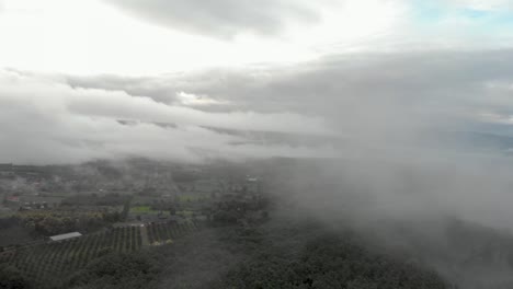 Cinematic-aerial-drone-shot-flying-through-misty-clouds-on-cold-morning-in-thailand-countryide-to-reveal-remote-village-in-valley-on-mountainous-hillsides