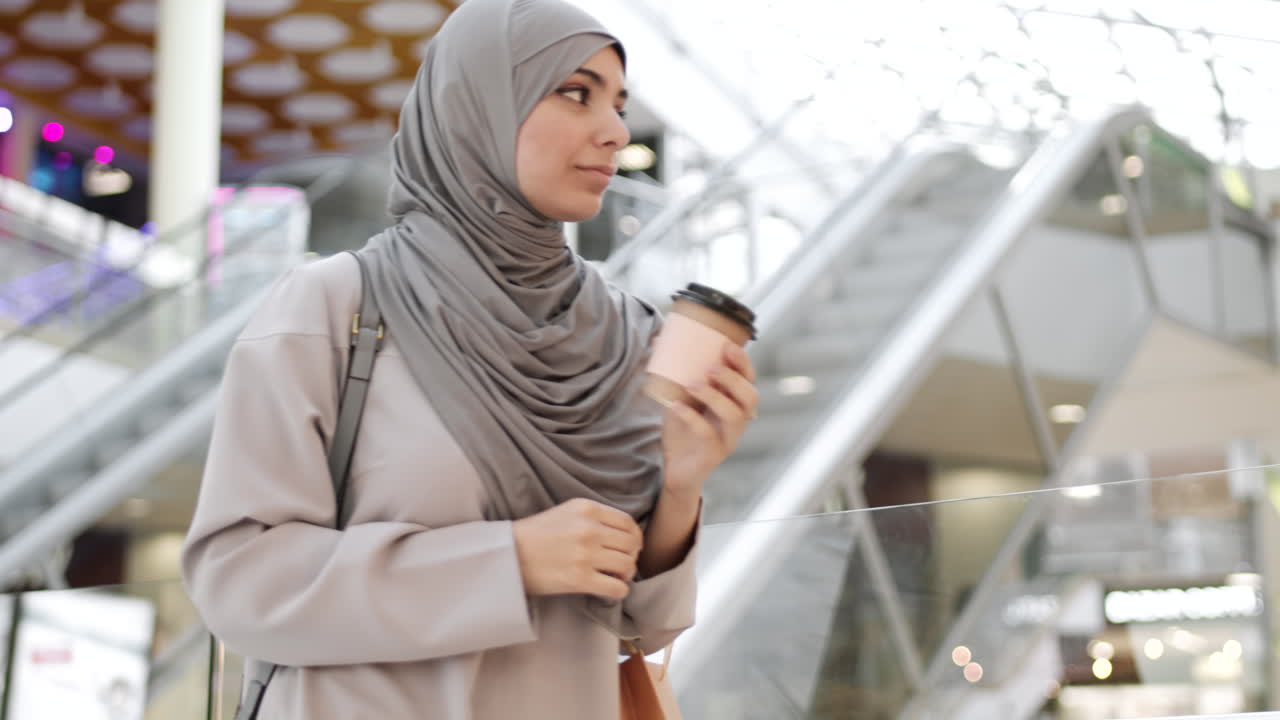 Donna musulmana che fa shopping e beve caffè in un centro commerciale.