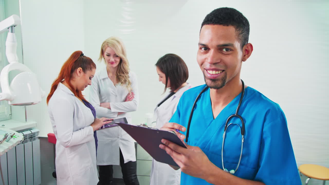 Doctors in the dental office. Three talking nurses and one noting doctor looking into the camera