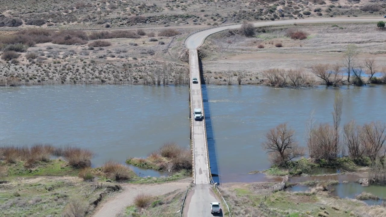 Aerial view of cargo truck and suv crossing narrow bridge La Rinconada. Neuquén, Patagonia, Argentina