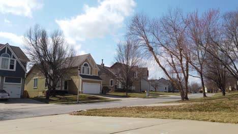 Looking-down-a-neighborhood-street-with-yellow-house-it's-very-windy-trees-are-blowing