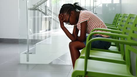 upset girl sitting on chair in corridor