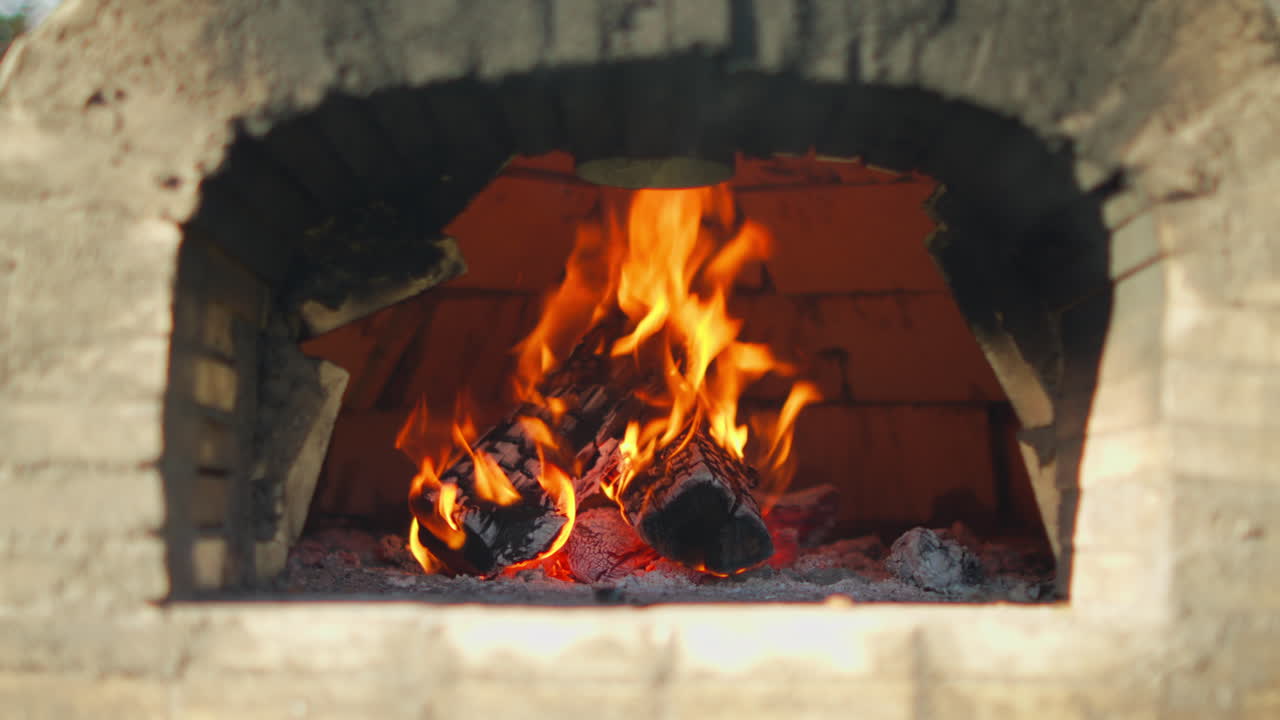 Outdoor stone oven with burning logs and bright flames at the entrance