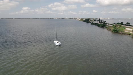 Panning-shot-around-a-sailboat-on-sunny-day-with-highway-in-background