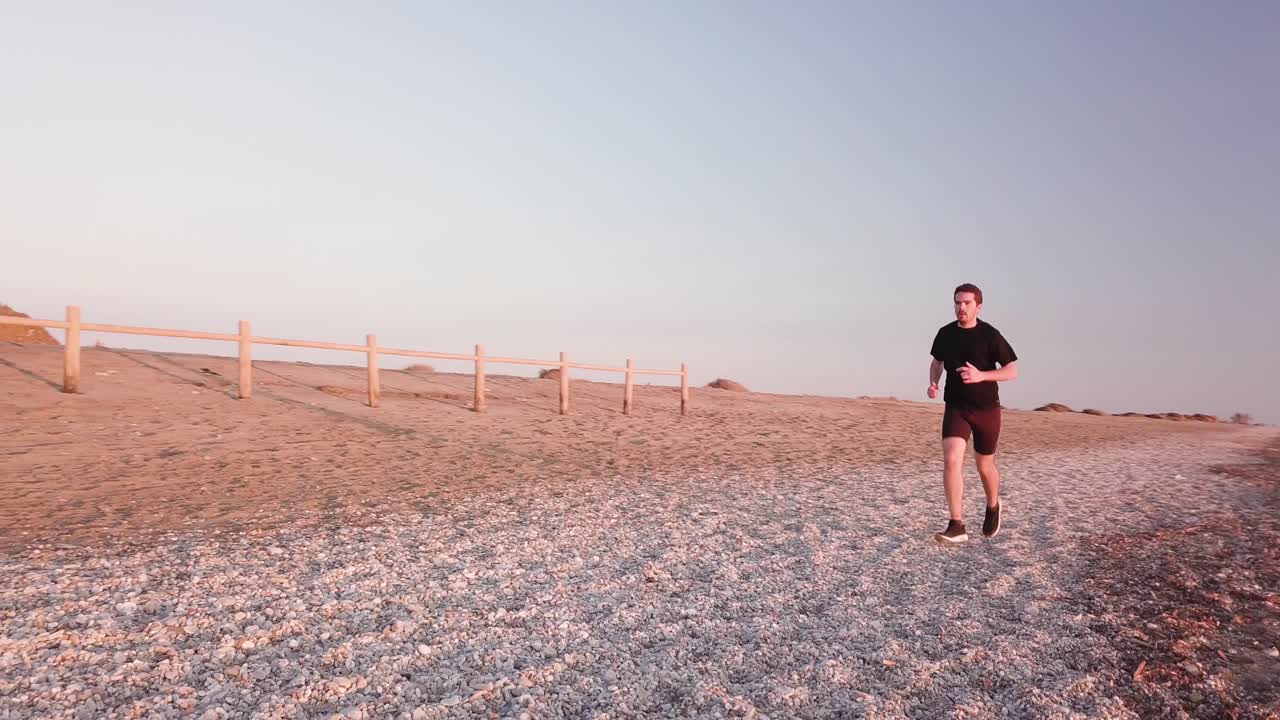 Young runner man training on beautiful sunset at beach