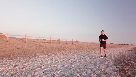 young runner man training on beautiful sunset at beach