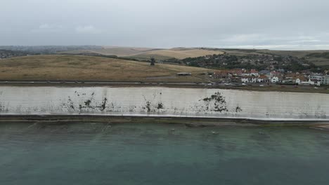 Aerial-seaside-pan-across-white-chalk-cliffs-of-Rottingdean,-England