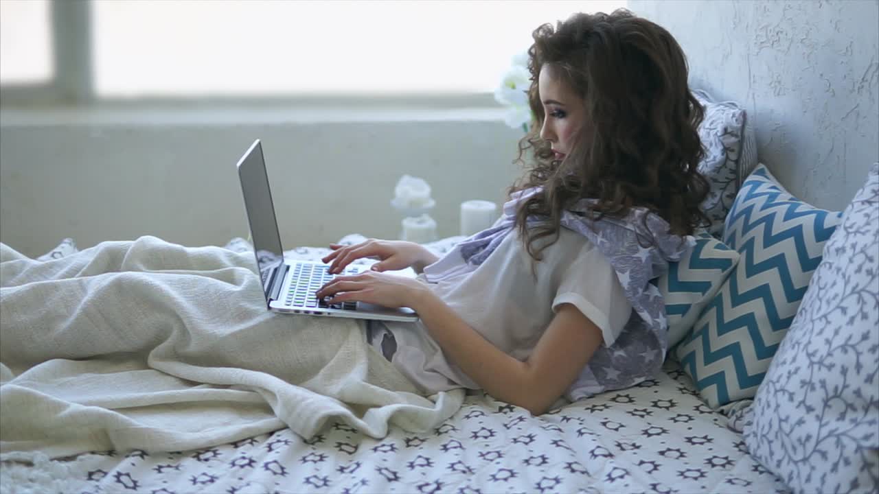 mujer trabajando en una computadora portátil en la cama