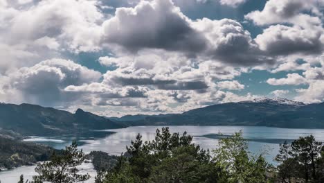 thick white-gray clouds whirling and moving above the calm blue water of the hardanger fjord