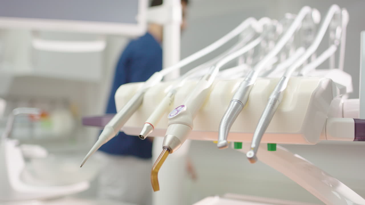 Shallow focus on dental tool set as dentist walks behind in slow motion