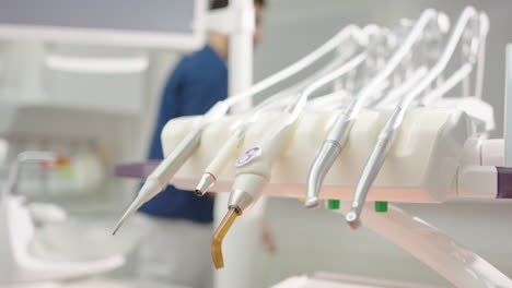 shallow focus on dental tool set as dentist walks behind in slow motion