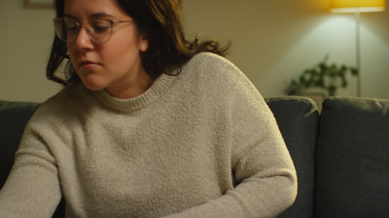 mujer joven pasando la noche en casa acostada en el sofá tomando una llamada en el teléfono móvil