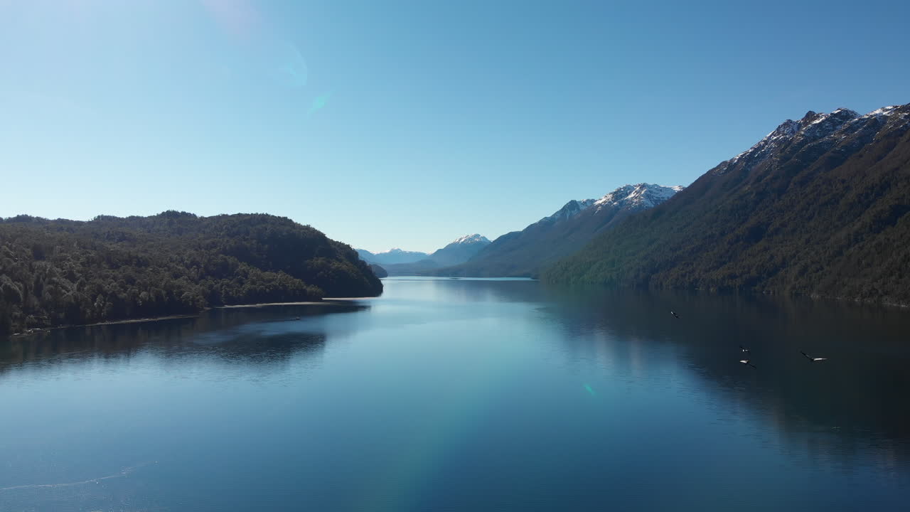 Yakınından bir kuş sürüsünün geçtiği bir gölün drone görüntüsü.