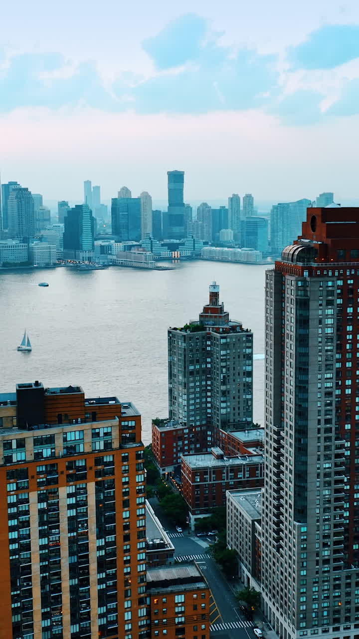 Looking at New York skyscrapers from across the river. Majestic building on both sides of Hudson. River transport is on water. Top view. Vertical video
