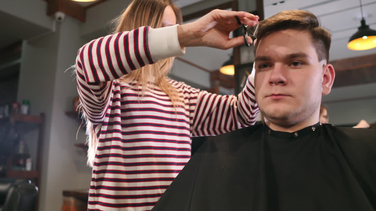 vista trasera de un cliente visitando a un peluquero y un peluquero en una barbería.