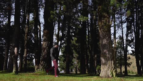 Stylish-camper-walking-through-a-large-pine-forest