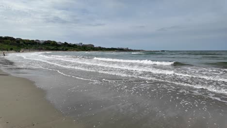 Walking-on-the-Beach-on-a-Sunny-Day-with-Waves-Slowly-Breaking-on-the-Shoreline,-Romania