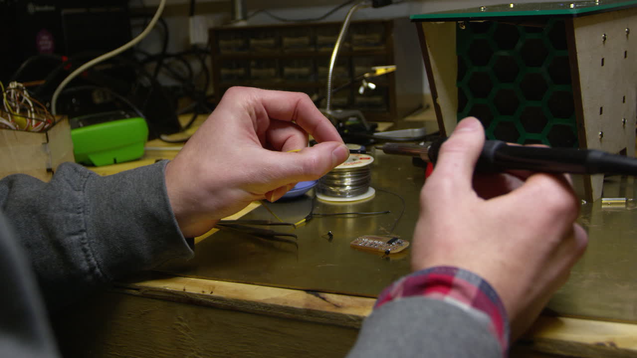 hombre soldando un cable a una placa de circuito, de cerca de las manos, filmado en r3d