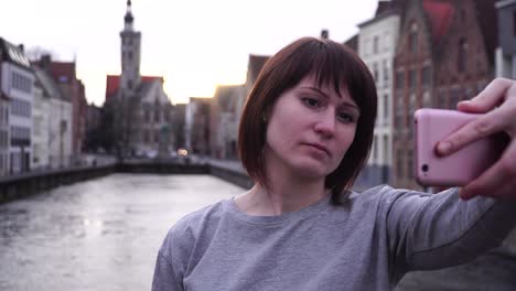 chica turista haciendo selfie en su teléfono inteligente al atardecer en bruges, bélgica