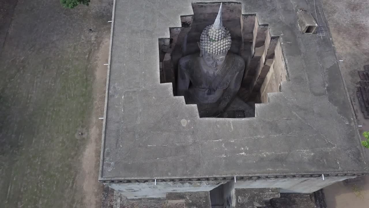 Aerial,ascending over the roof of Wat Si Chum Buddha Statue at Sukhothai,details of the statue from the top inside the building.