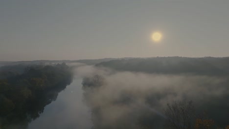 high-resolution drone footage: early morning river with rising mist, framed by autumn-colored trees