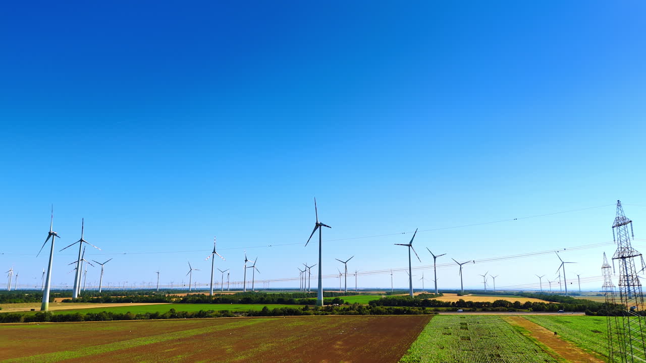 Wind turbines rotate in the wind on sunny summer day. Green energy concept. Drone footage
