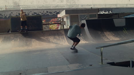 teenagers friends practicing together on scooter and skate board at skatepark