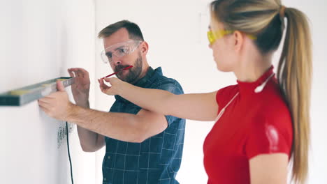 constructor with female colleague checks wall level in room