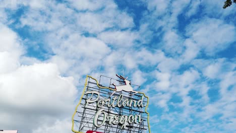 4k-Inclinado-Hacia-Abajo-Desde-Un-Marco-De-árbol-A-La-Derecha-Con-Un-Cielo-Parcialmente-Nublado-A-Una-Toma-Amplia-Del-Marco-Central-Del-Letrero-Del-Casco-Antiguo-De-Portland,-Oregón