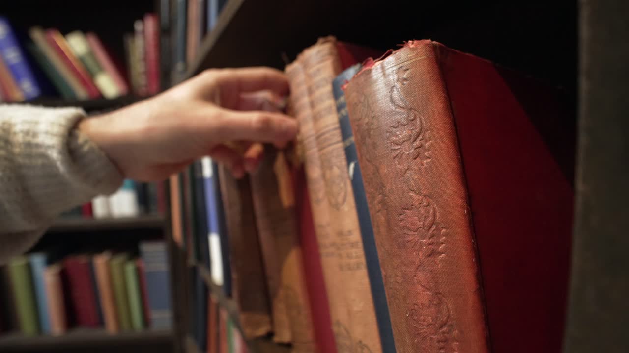 busca a mano en la estantería, tirando, reemplazando y agarrando los libros que necesitan