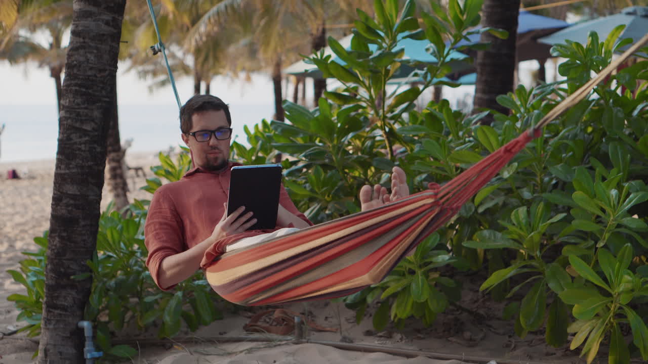 Uomo che si rilassa in un'amaca su una spiaggia tropicale