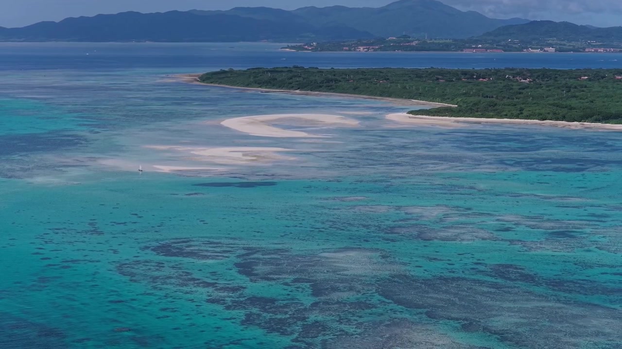 Filmato aereo orizzontale che esegue una panoramica lenta verso sinistra mentre si allontana con un carrello all'indietro sopra i banchi di sabbia, le barriere coralline e le acque turchesi di Kondoi Beach e Kaiji Beach, Isola di Taketomi, Okinawa, Giappone