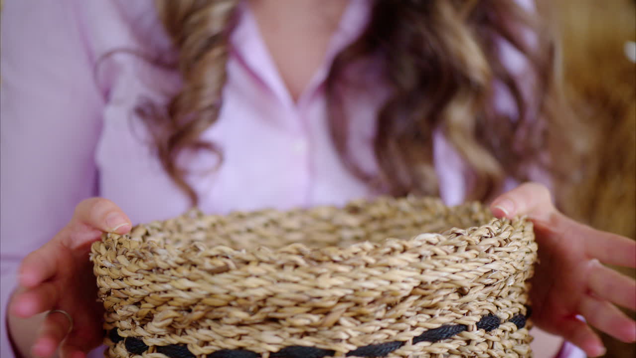 Woman playing with a white bunny in the barn near square hay bales, in daylight
