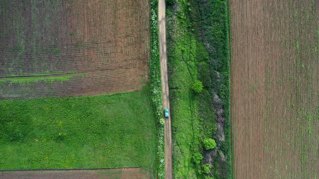 물 행상이 많은 젖은 흙길을 운전하는 차를 따라가는 드론